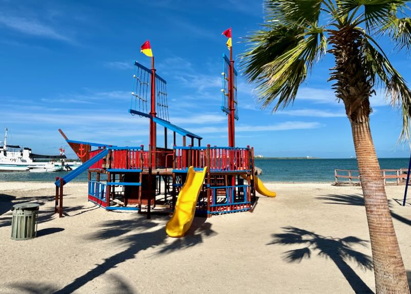 A red and blue playground ship with a yellow slide.