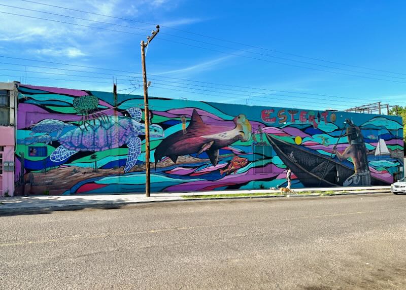 A colorful wall mural of sea turtles, fish, and a man rowing a boat.