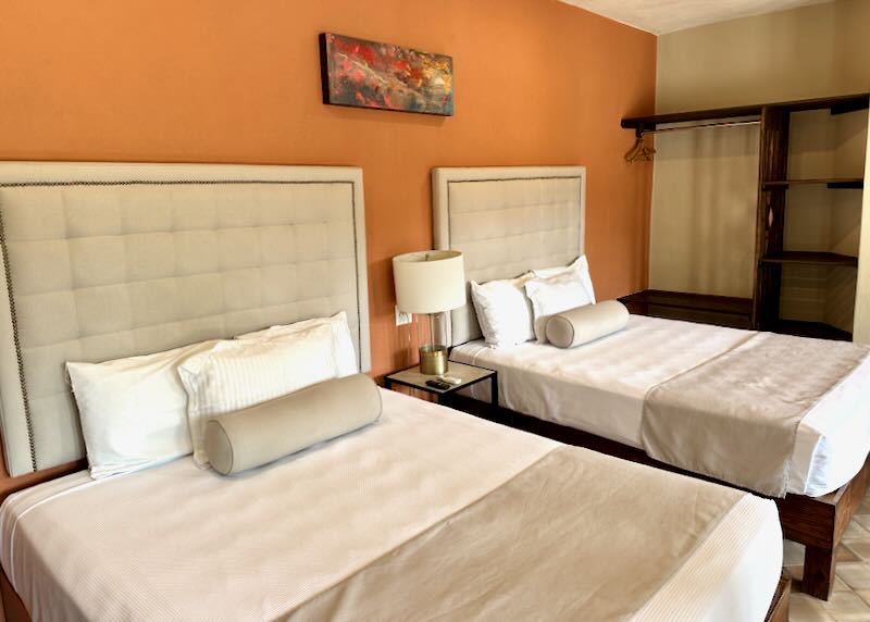 Two tan beds in an orange painted room.