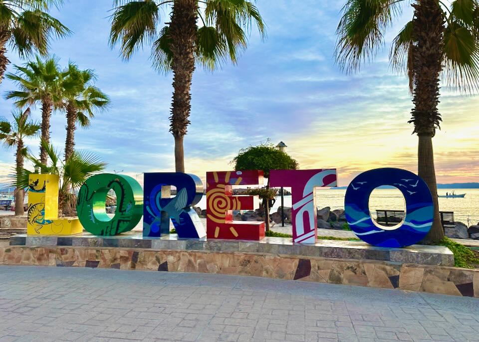 A colorful sign that reads, Loreto, on the beach pathway.