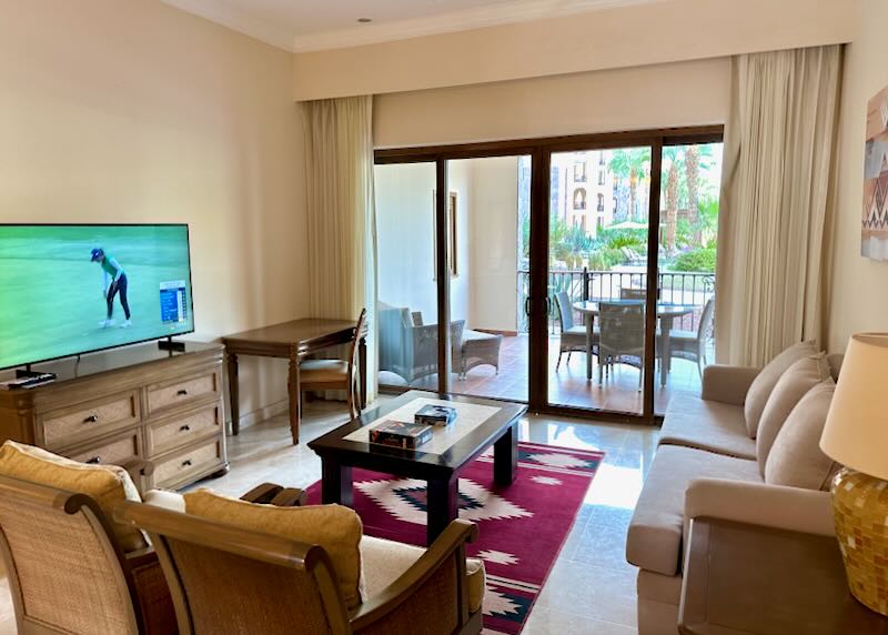 A living room with a sofa, two chairs, and a gold game on the tv.