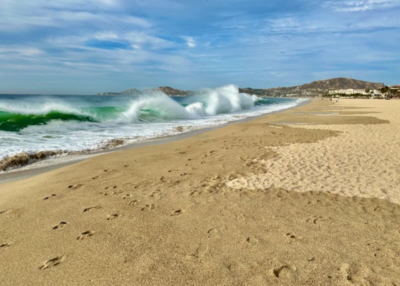 A wild wave hits the yellow sand of the beach.