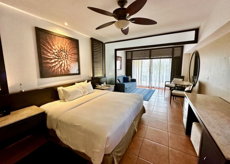 A white bed in a hotel room with a photograph above it.