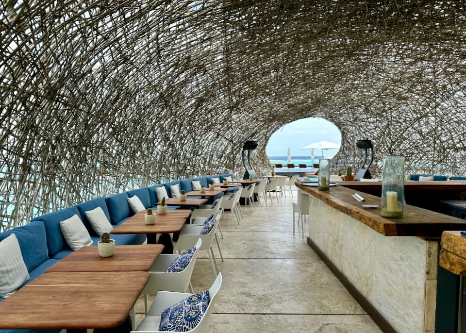 A woven nest restaurant with table along its walls.