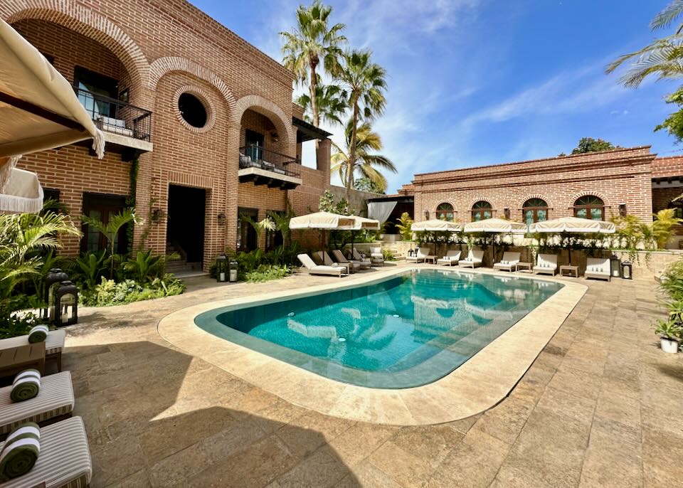 A blue pool is surrounded by tan lounge chairs.