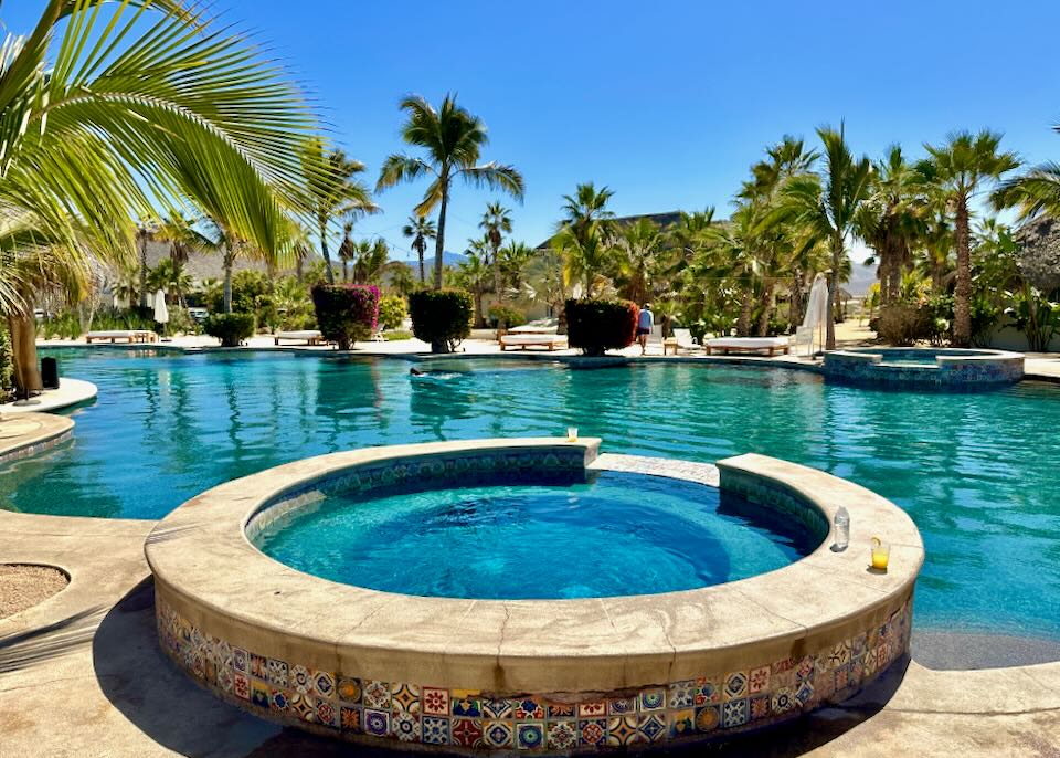 A round hot tub sits on the edge of a pool.