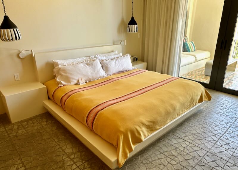 A bed with a yellow bedspread sits in a hotel room.