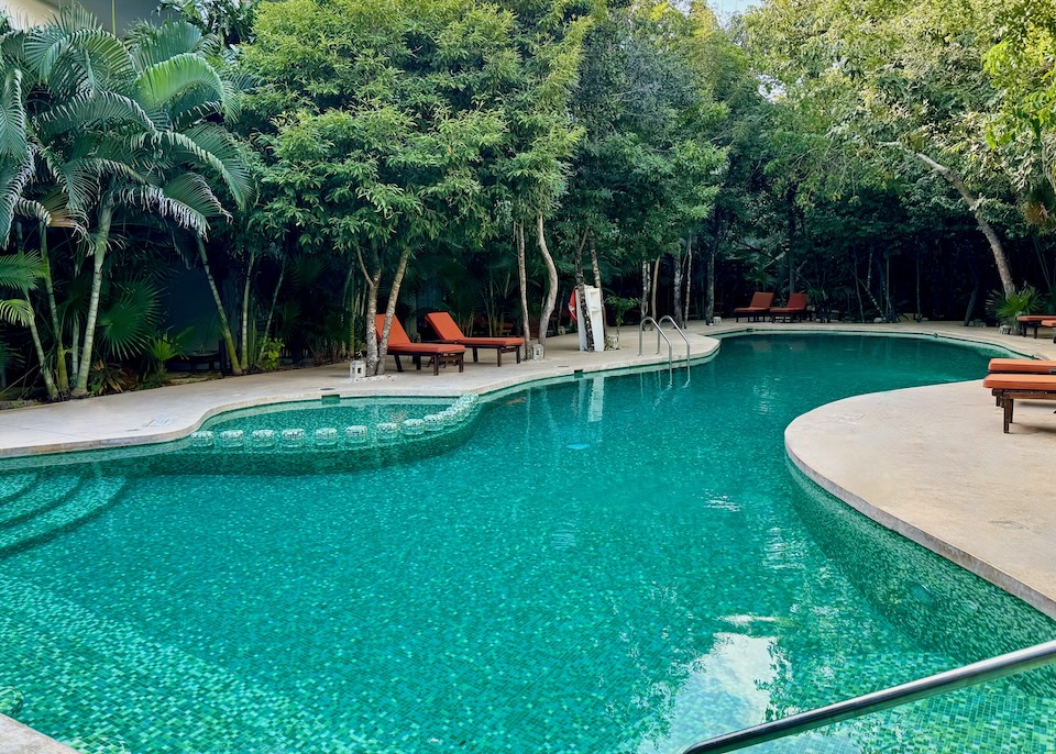 A freeform pool with an attached kids’ section set in the jungle at Kimpton Aluna hotel in Tulum.