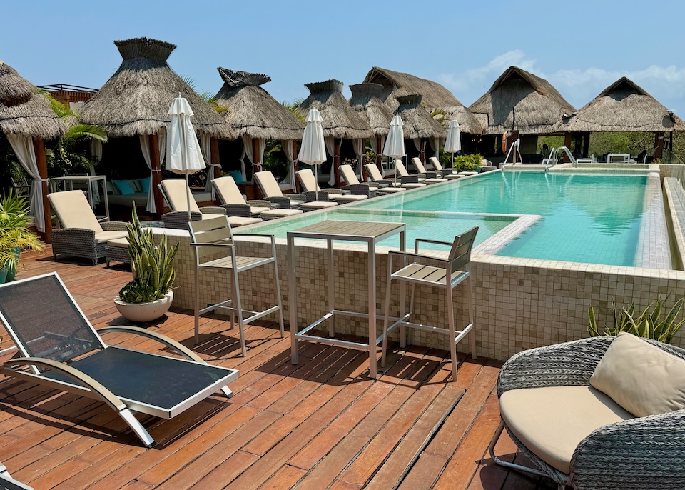 A rooftop pool with attached jacuzzi surrounded by thatched-roof Bali beds at Naay hotel in Tulum.