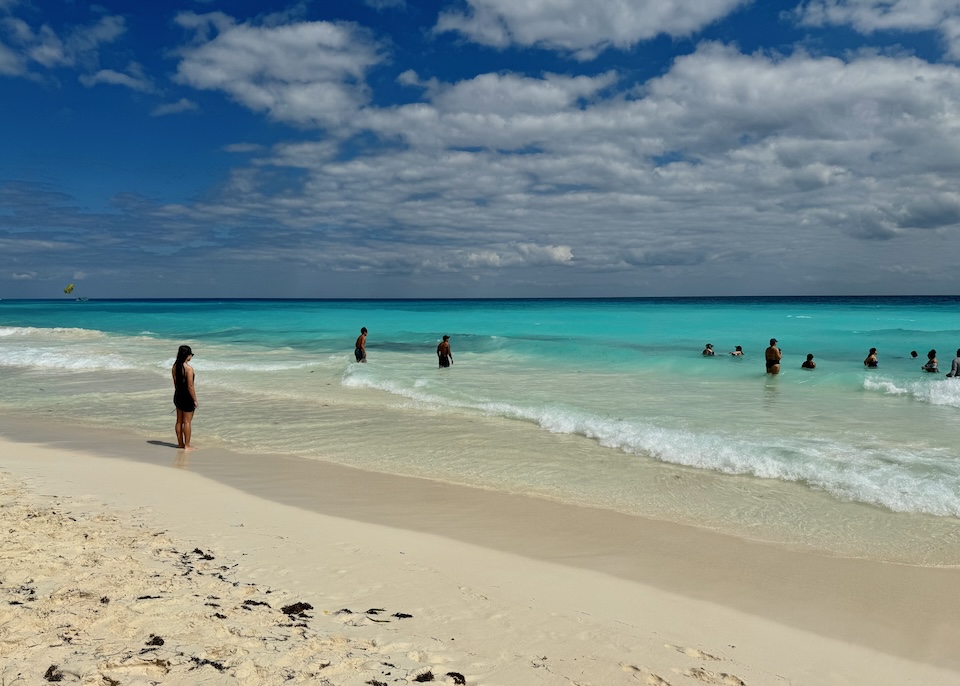 People wading and swimming in small ocean waves in the Middle Hotel Zone of Cancun.