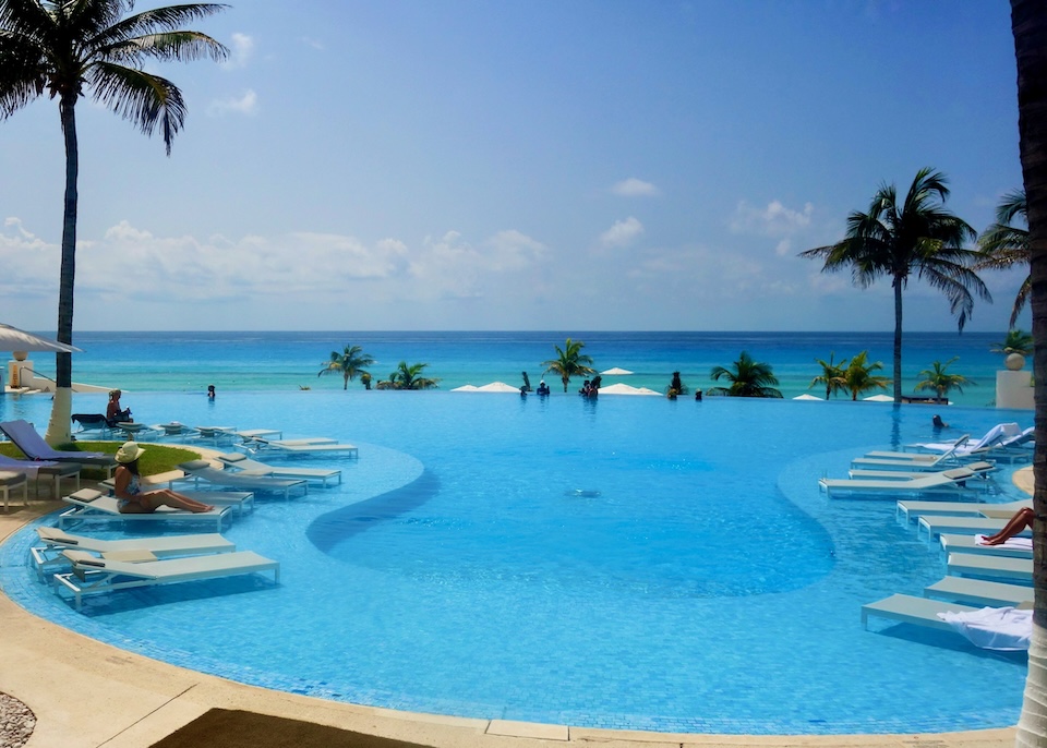 A freeform infinity pool with sunken sunbeds facing the ocean at Le Blanc resort in Cancun.