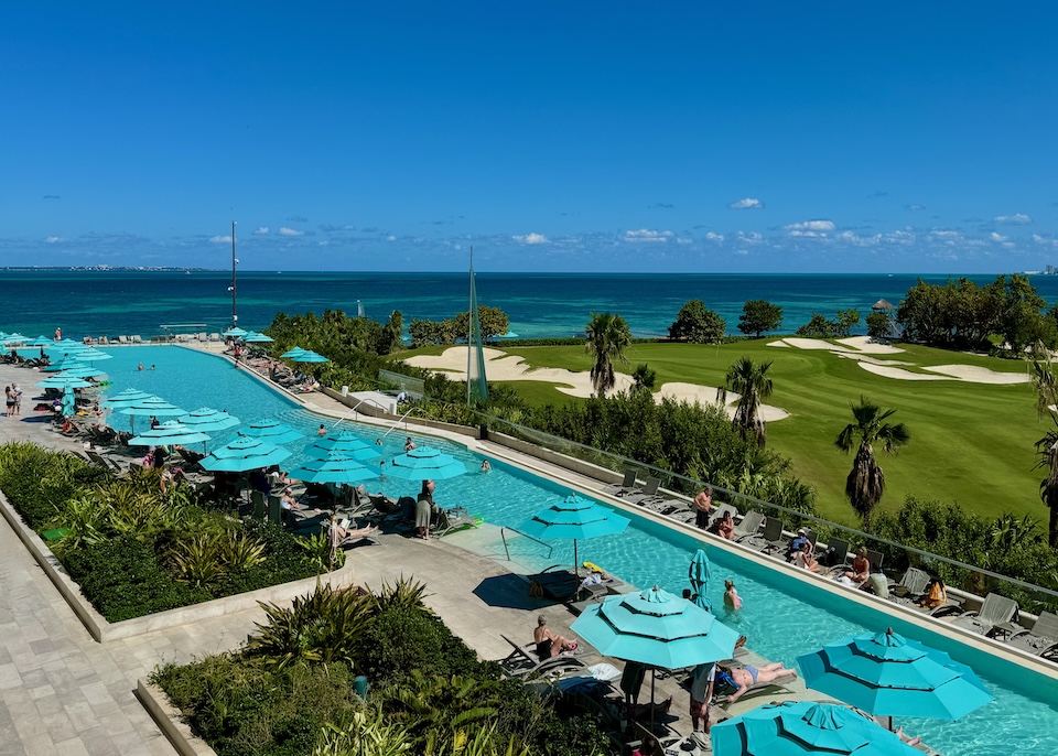 An ultra-long pool alongside a golf course, both facing the ocean, at Dreams Vista in Puerto Juarez, Cancun.