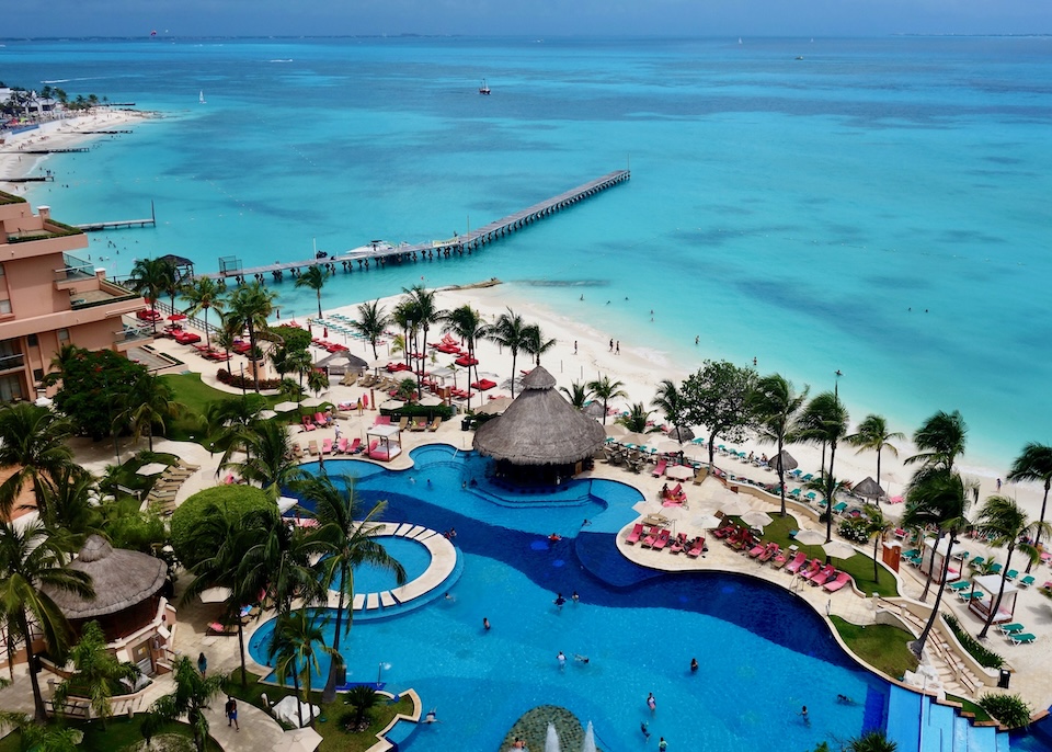 A freeform pool on the beach and a pier jutting into the ocean at Grand Fiesta Americana resort in Cancun.