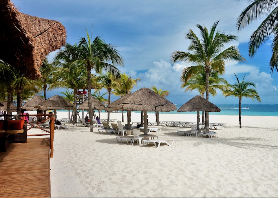 A wide, white beach with a deck a sunbed-umbrella sets at the InterContinental Presidente resort in Cancun.