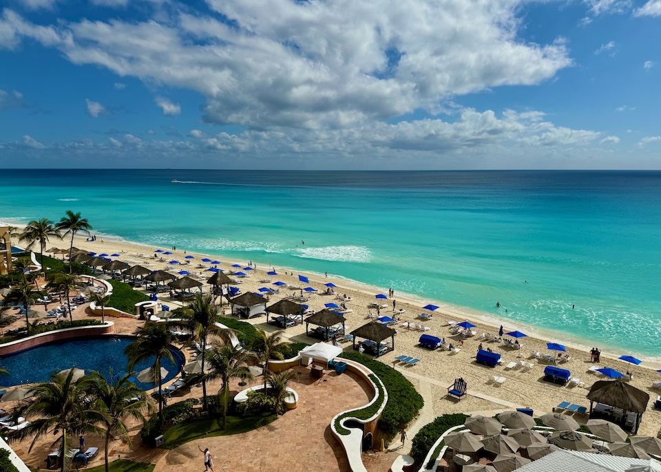 A kidney-shaped pool on a terracotta deck above the beach and ocean at Kempinski resort in Cancun.