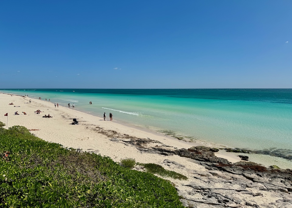 A beach with a rocky patch in the foreground in the North Beach Zone of Tulum.