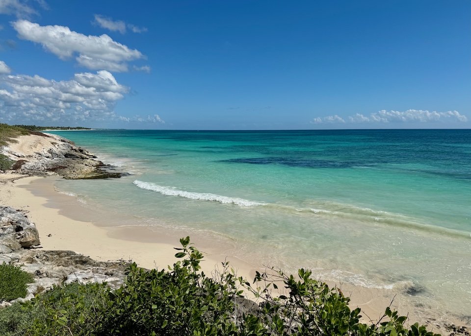 A beach with some rocks inland away from the water in the Beach Town area of Tulum.