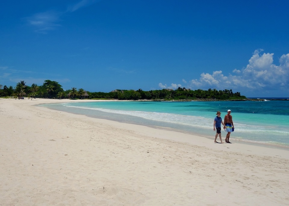 Two men walking on an immaculate stretch of white sandy beach in the South Riviera Maya north of Tulum.