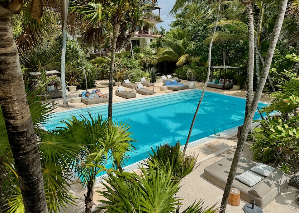 An infinity pool with a glass front in a jungle garden setting with sunbeds on all sides at Jashita Hotel on Soliman Bay near Tulum.