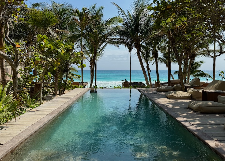 An ocean-view infinity pool with a wooden deck and palm trees at Xela hotel in the South Beach Zone.