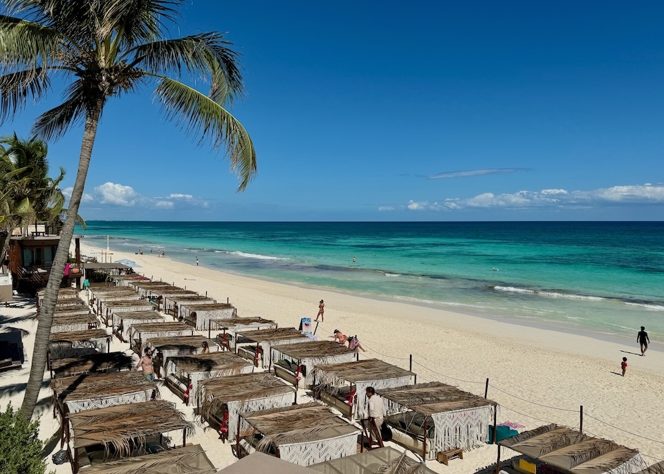 A pristine beach lined with palm-covered Bali beds at La Zebra hotel in the South Beach Zone of Tulum.