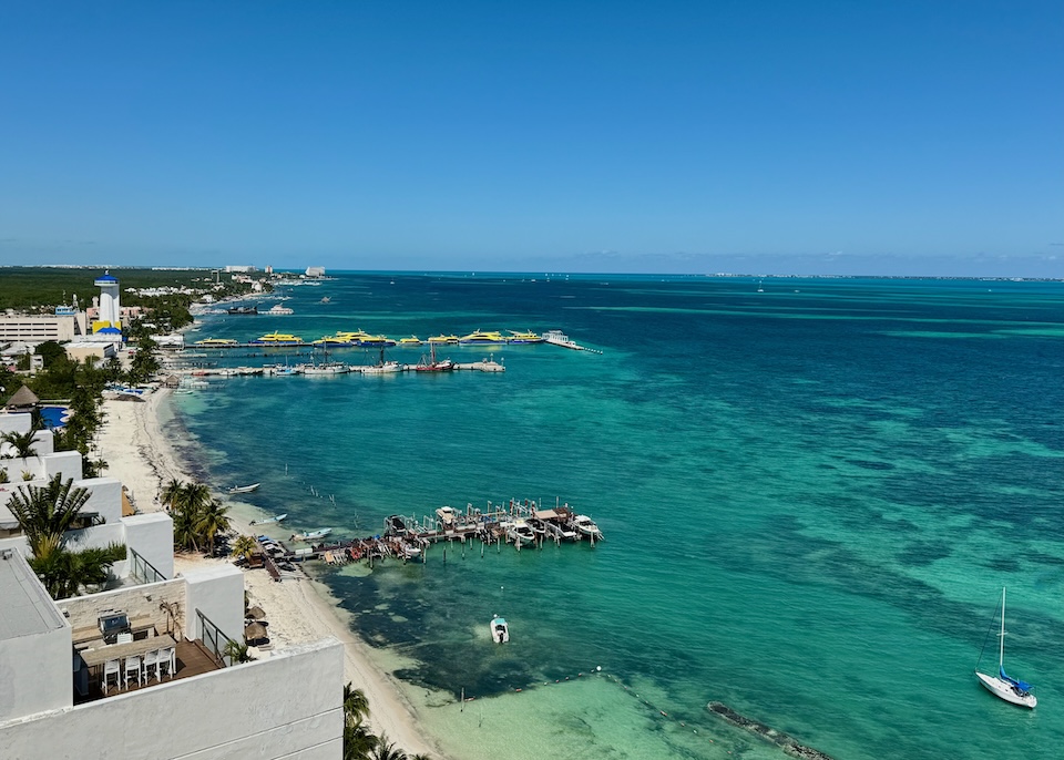 View from above Puerto Juarez showing the ferry port and two piers in front of a long beach.