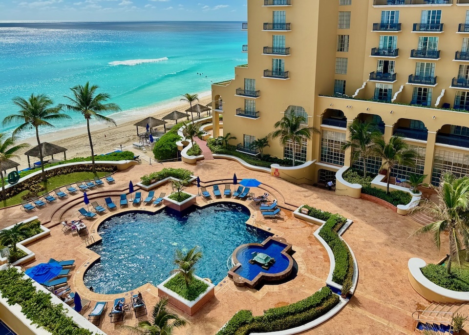 An elegant pool in an unusual shape facing the beach and ocean at Kempinski resort in the Middle Hotel Zone of Cancun.