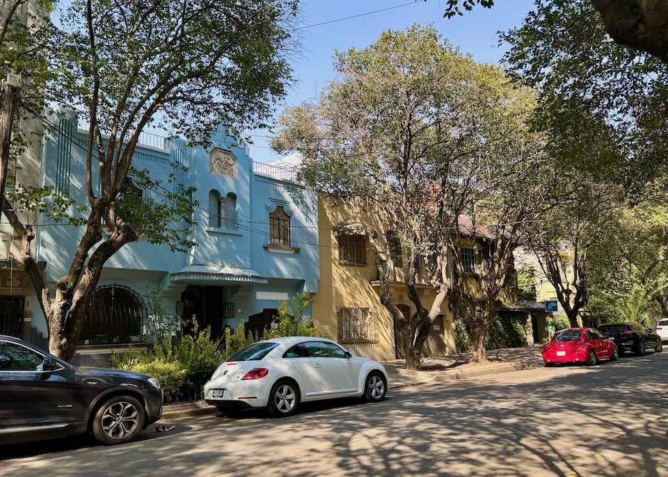 A tree-lined street with Art Deco building façades painted in pastel colors in La Condesa.