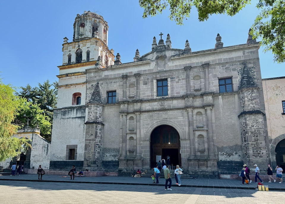 The stone-clad Mexican Baroque façade of the Church of San Juan Bautista on the main square in Coyoacán.