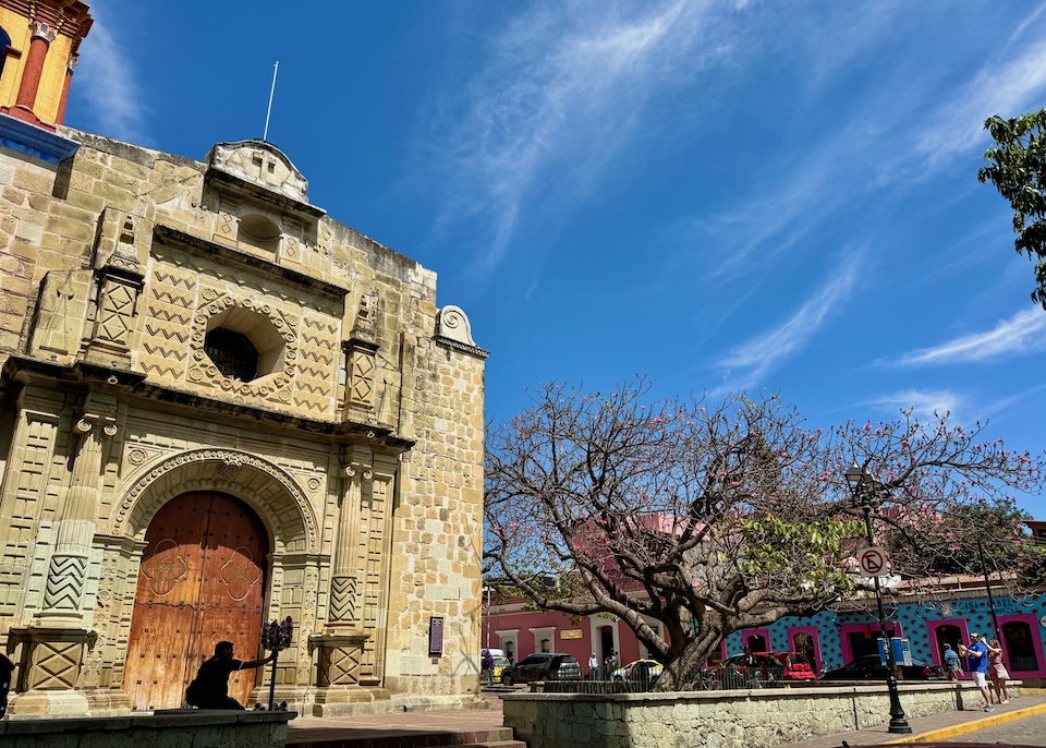 The ornate stone façade of San Matias Church in Oaxaca with colorful buildings in the background in the Jalatlaco neighborhood of Oaxaca.