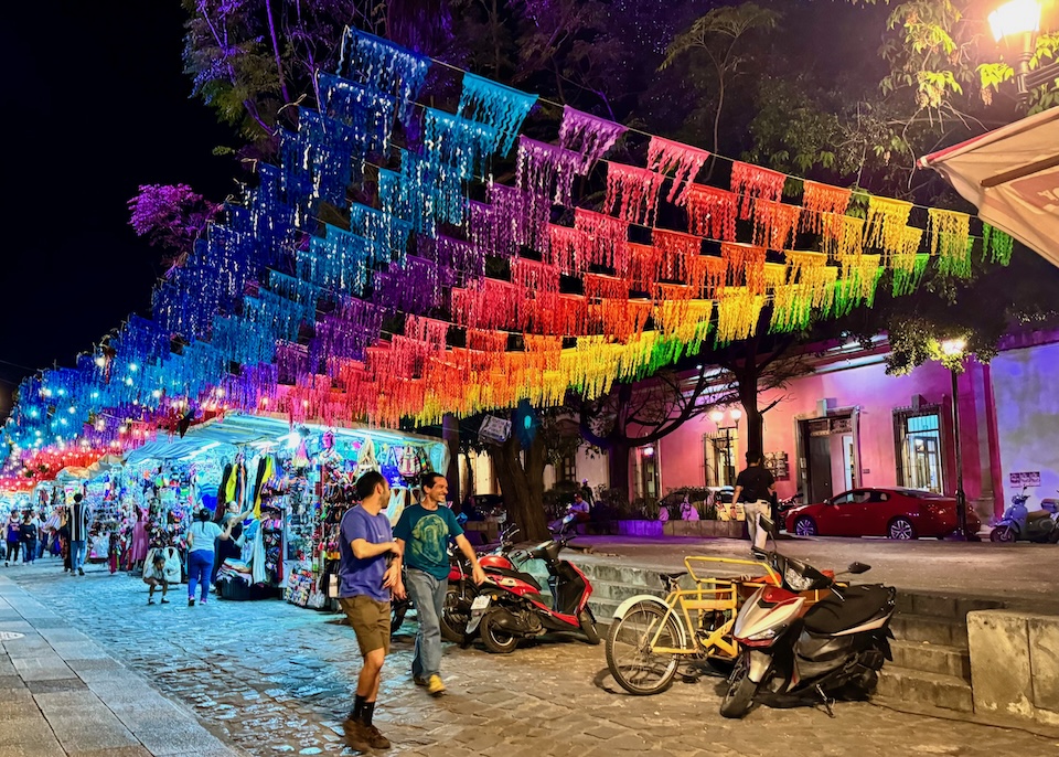 A night market under rainbow papel picado in the Santo Domingo neighborhood of Oaxaca.