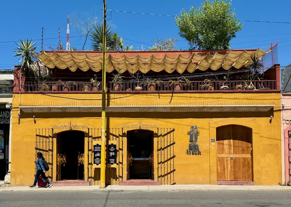 A deep gold building with a rooftop terrace under a canopy at Ayook hotel in Oaxaca.