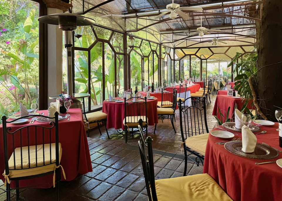 A formal dining room inside a greenhouse at Hacienda Los Laureles hotel in Oaxaca.