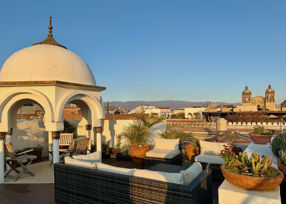 A rooftop terrace with a white gazebo and a direct view of Santo Domingo de Guzmán church at the hotel Palacio Borghese in Oaxaca.