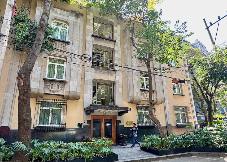 The low-rise, Art Deco-style Casa Mali with vertical accents, geometric patterned windows, and different shades of stonework at Casa Mali hotel in Mexico City.