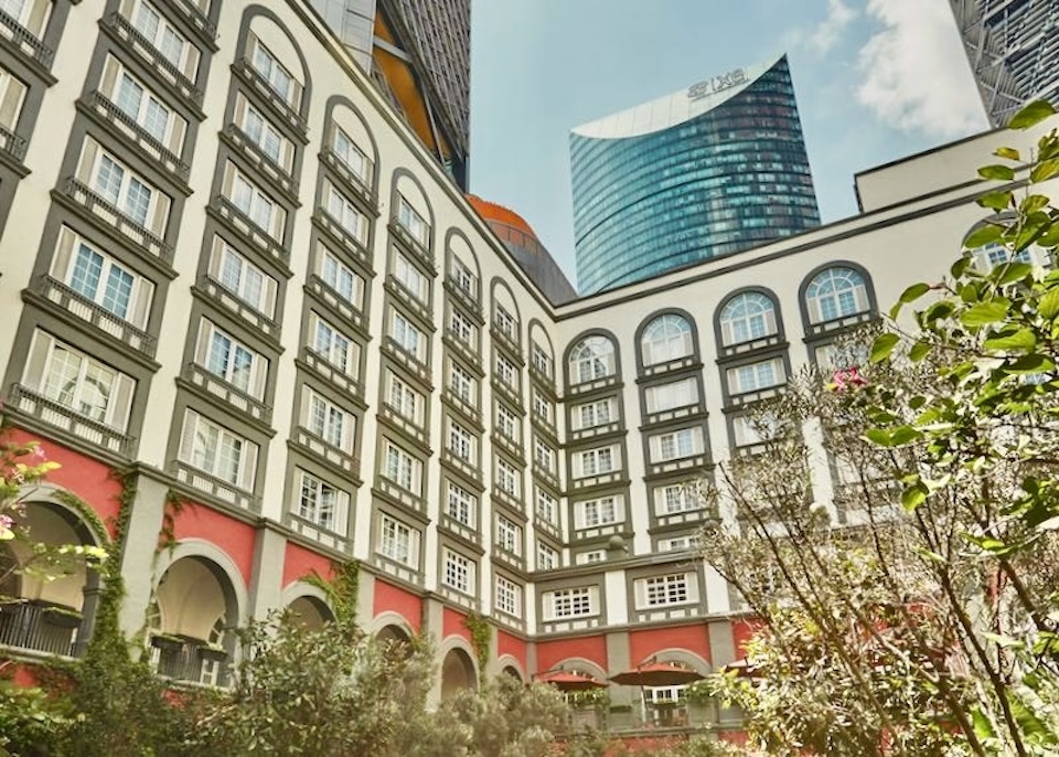 View of high-rises from inside the garden courtyard of a modern building with hacienda-style arches and arcades at the Four Seasons hotel in Mexico City.