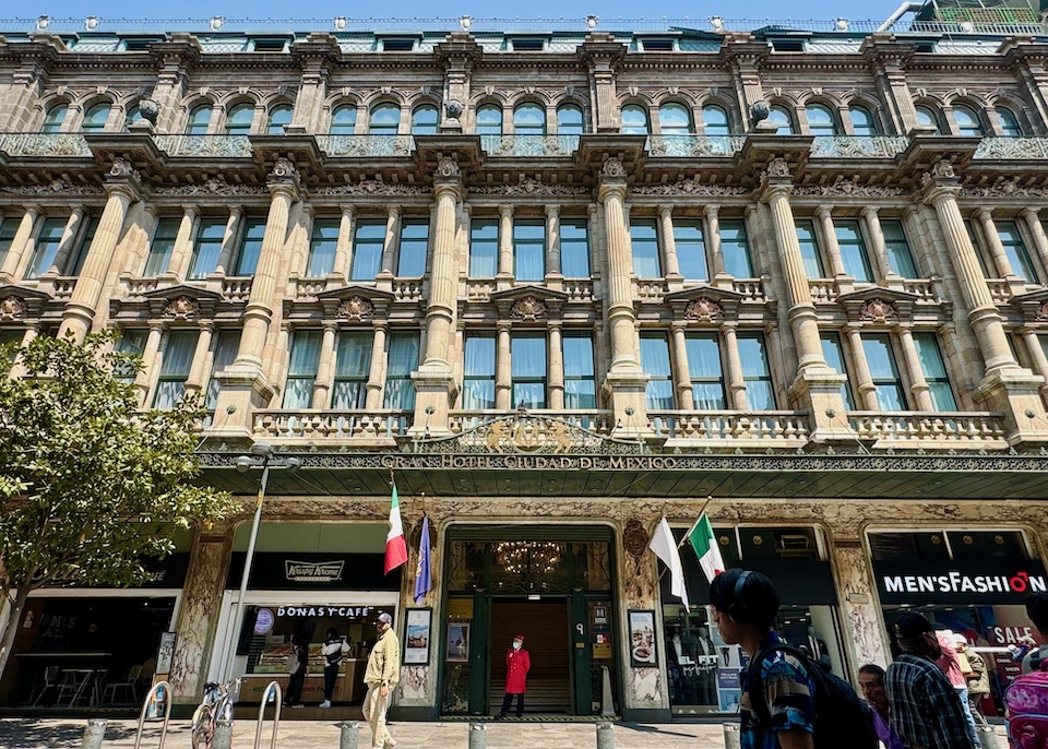 Ornate, neo-classical, 1899 building with columns and capitals on the upper three stories, arched windows on the top floor, and a marble façade on the ground floor at Gran Hotel Ciudad de México.