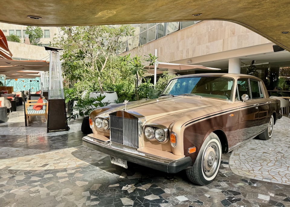 A vintage Rolls Royce in two shades of brown parked in an interior courtyard of the restaurant La Terrazza at the Mondrian hotel in Mexico City.