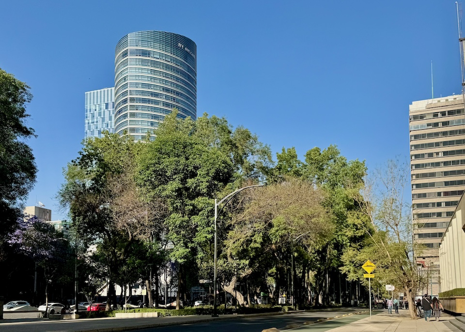 The cylindrical, high-rise tower of St. Regis Hotel rises above the trees in Mexico City.